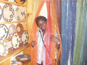 Cissy poses amongst the multicoloured raffia - used to weave baskets Rubona Basket Weavers' Association